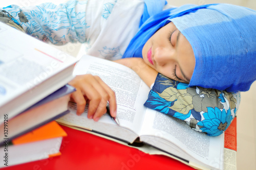A young muslim woman falling asleep while reading a book