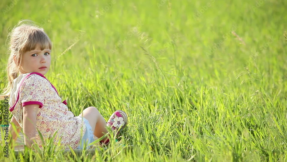 Offended by a little girl looks at camera. In the grass. Offended by a little girl looks at camera. In the grass.