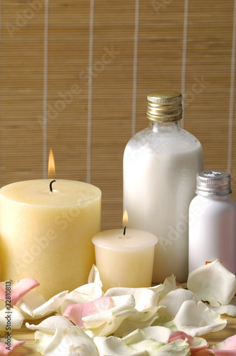 Body oils  rose petals and candle on bamboo stick straw mat