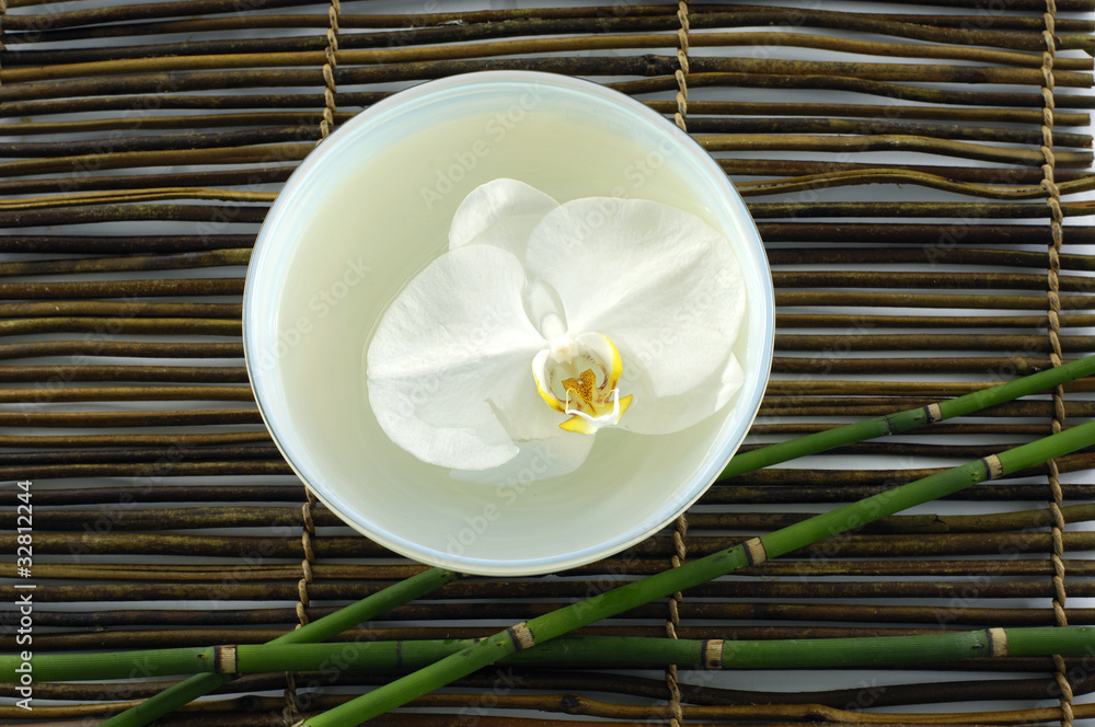 bowl of white orchid with thin steam bamboo on stick straw mat bowl of white orchid with thin steam bamboo on stick straw mat