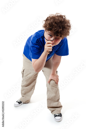 Boy using magnifying glass on white background