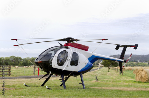 Small helicopter in paddock with hay-bales photo