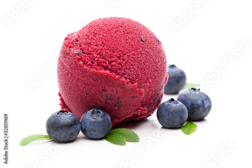Tableau sur toile Eine Kugel Eis mit Heidelbeeren auf weißem Hintergrund