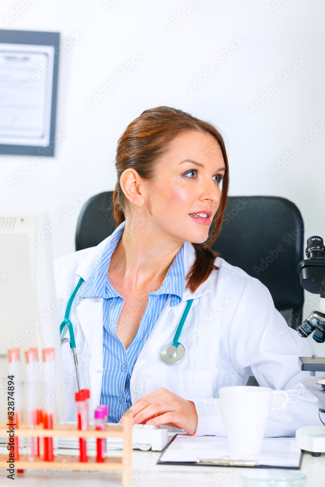 Medical doctor woman sitting at office table and looking away. Medical doctor woman sitting at office table and looking away.