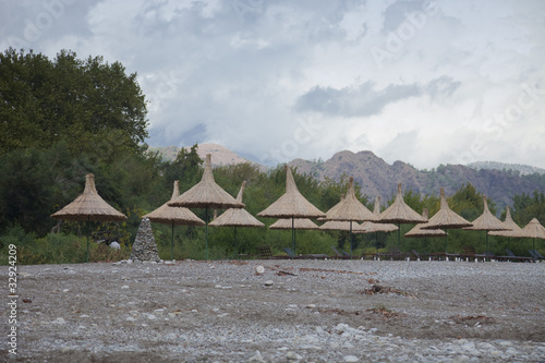 Straw Umbrellas with Sun Loungers on Beach photo