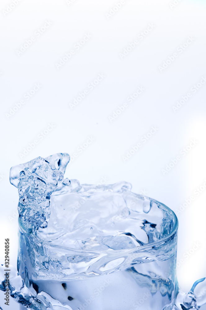 Mineral water splashing out from translucent glass