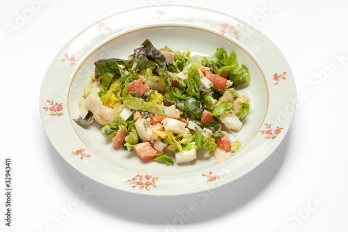 Тарелка с салатом на светлом фоне.