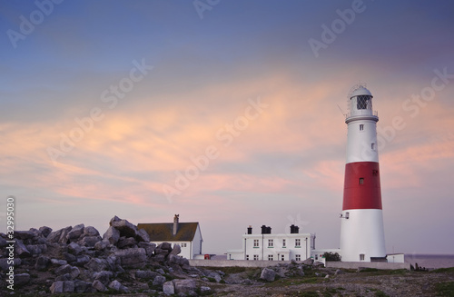 Victorian lighthouse on promontory of rocky cliffs during stunni