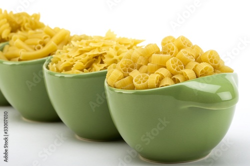 Assorted raw pasta noodles in green ceramic dish