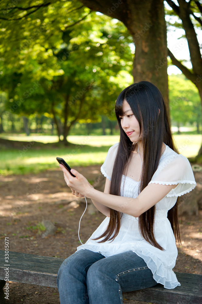 beautiful asian woman using a smartphone in the park beautiful asian woman using a smartphone in the park