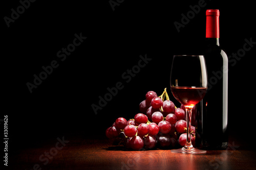 Wine glass and Bottle and red grapes on a wooden table