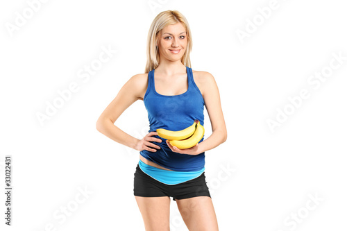 Portrait of a female athlete holding bananas