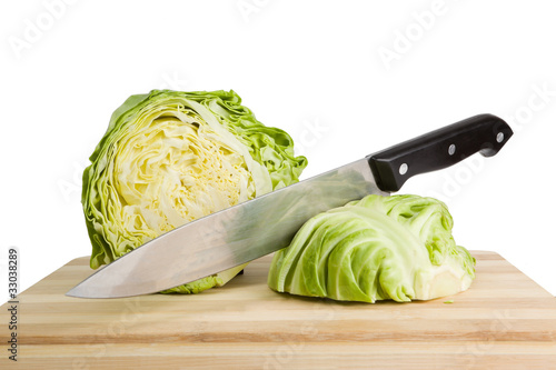 Fresh green iceberg lettuce with knife on wooden chopping board