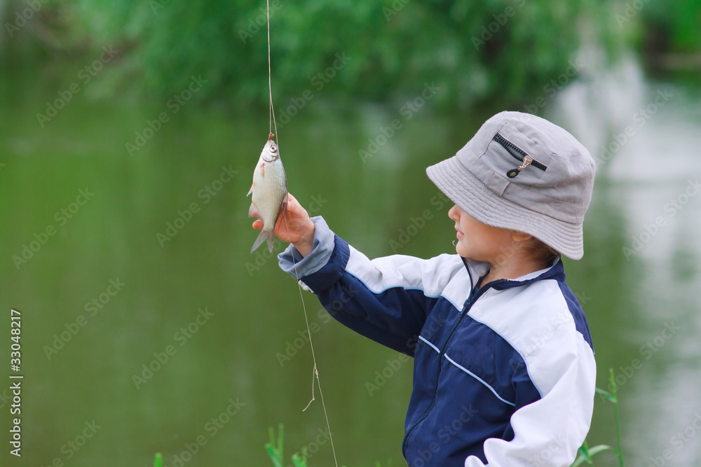 Young boy look at the caught fish Young boy look at the caught fish
