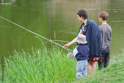 Mother and sons catch the fish on the river shore