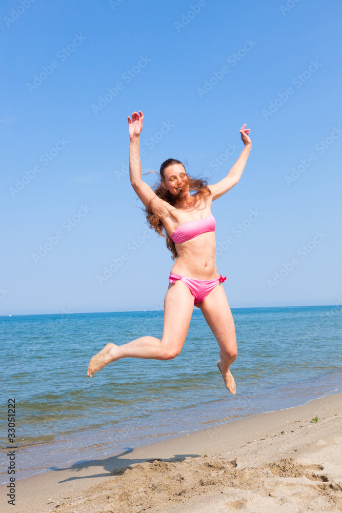 Happy Woman Jumping on the Beach at Seaside Happy Woman Jumping on the Beach at Seaside