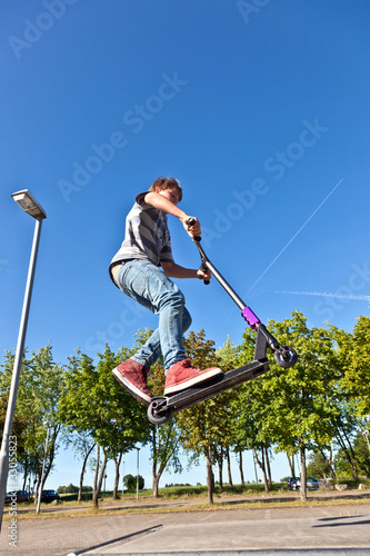 boy jumps with his scooter at the skate park