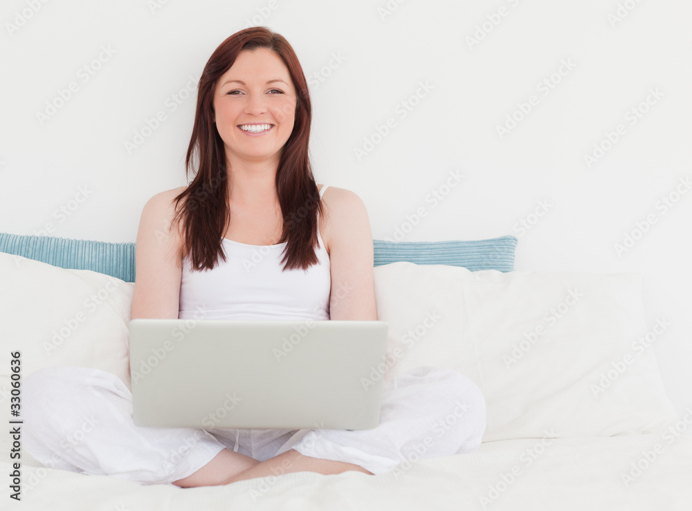 Pretty red-haired female relaxing with her laptop while sitting Pretty red-haired female relaxing with her laptop while sitting