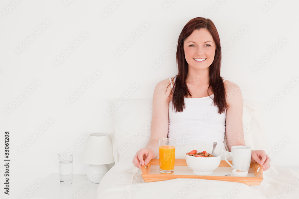 Attractive red-haired woman having her breakfast while sitting o Attractive red-haired woman having her breakfast while sitting o