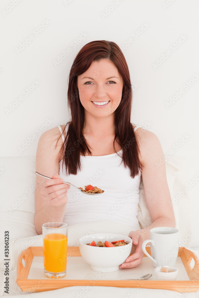 Gorgeous red-haired woman having her breakfast while sitting on Gorgeous red-haired woman having her breakfast while sitting on