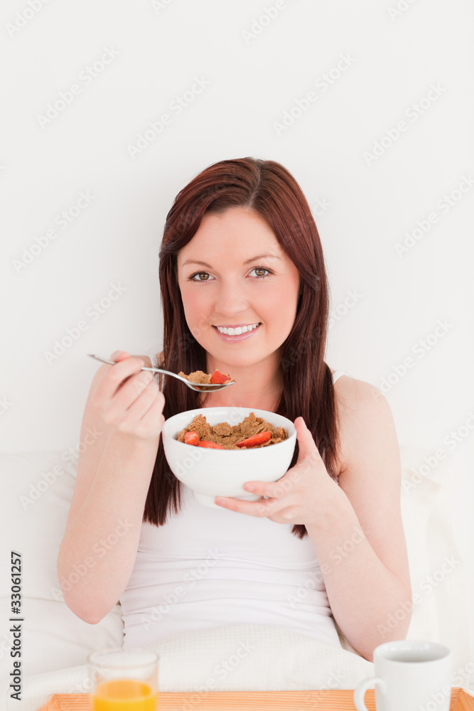Gorgeous red-haired female having her breakfast while sitting on Gorgeous red-haired female having her breakfast while sitting on