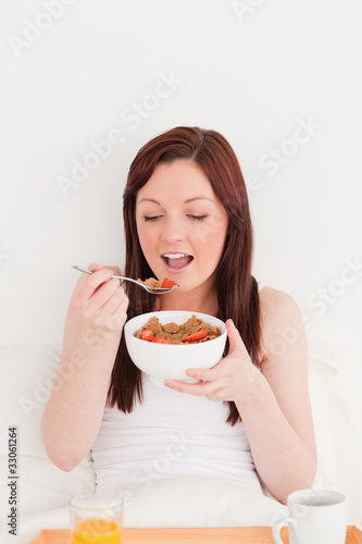 Good looking red-haired female having her breakfast while sittin
