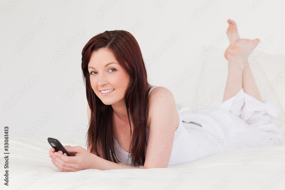 Attractive red-haired female writing a text on her mobile while Attractive red-haired female writing a text on her mobile while