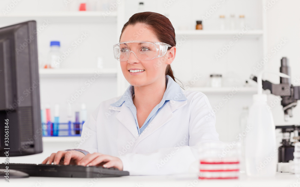Cute scientist typing a report with her computer Cute scientist typing a report with her computer