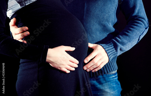 pregnant woman and her husband caressing her belly photo