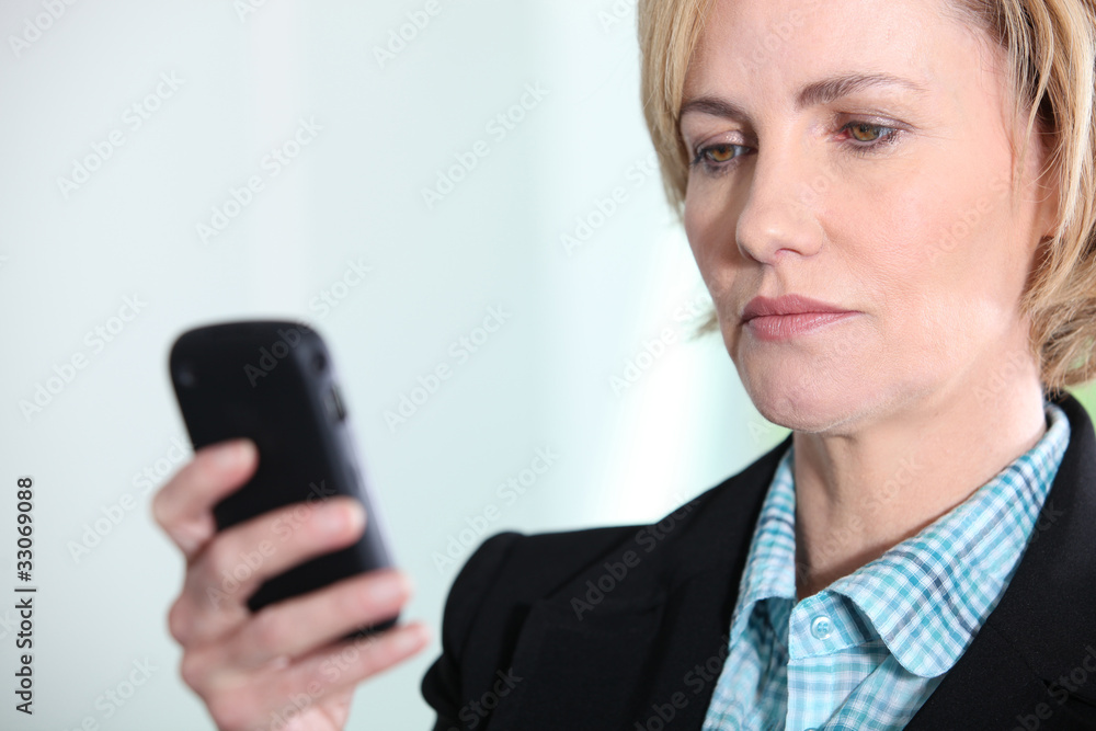 Blond woman looking at mobile telephone screen Blond woman looking at mobile telephone screen