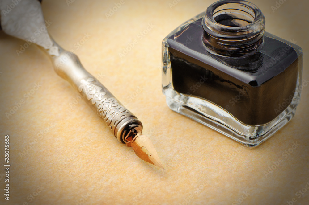 Feather quill and inkwell on an old paper Feather quill and inkwell on an old paper