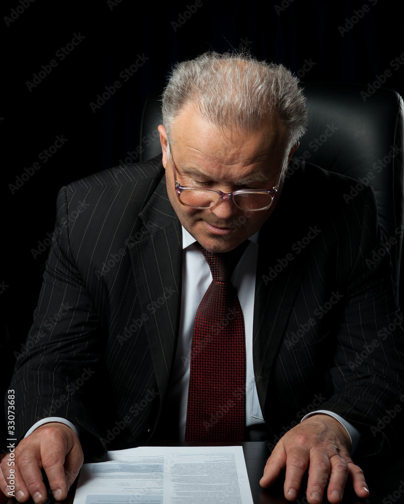 The elderly man in eyeglases reads the document The elderly man in eyeglases reads the document