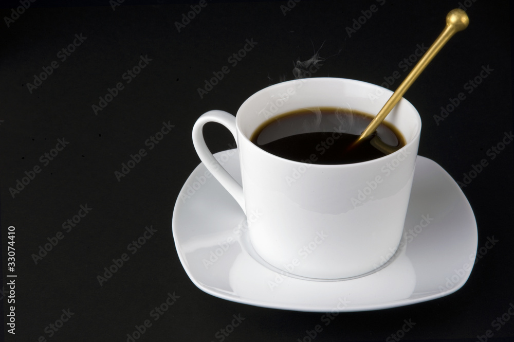 White cup of coffee with smoke, golden teaspoon isolated on blac White cup of coffee with smoke, golden teaspoon isolated on blac
