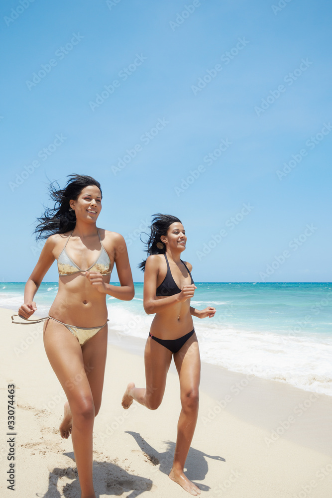 latina sisters in bikini on beach near caribbean sea