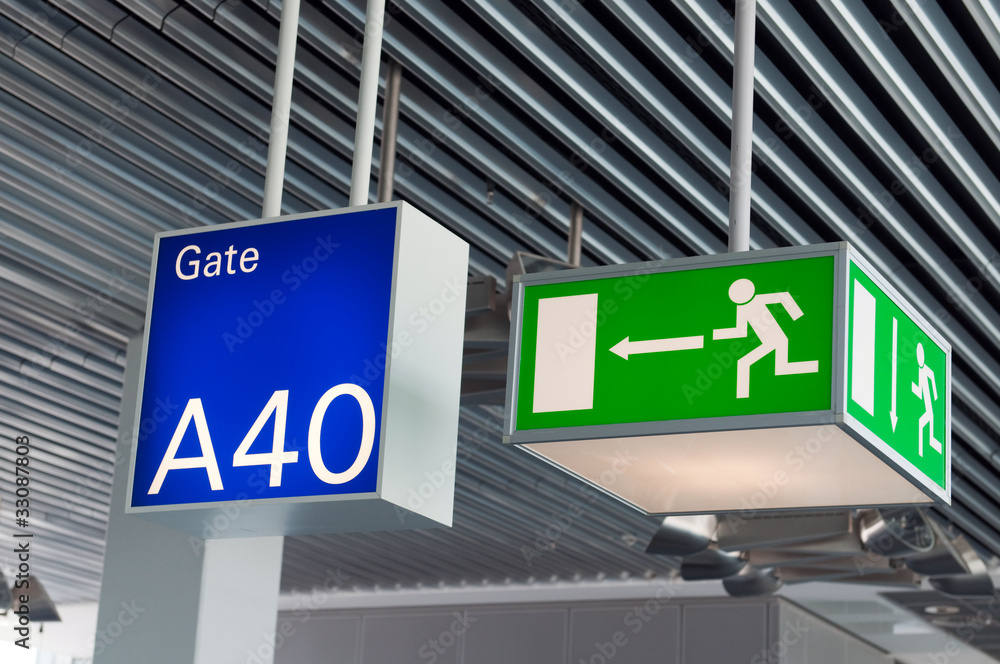 Green emergency exit sign,and blue gate sign in airport Green emergency exit sign,and blue gate sign in airport