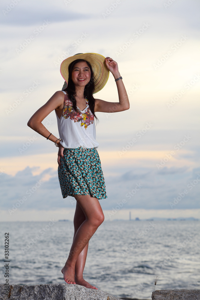Beautiful woman in dress standing on rock over sea