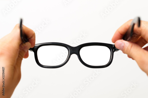 Two hands putting on thick black glasses
