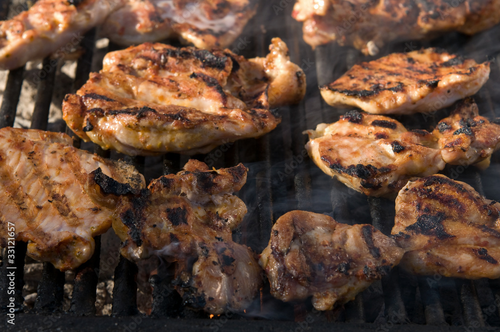 Pieces of grilled chicken on barbecue.