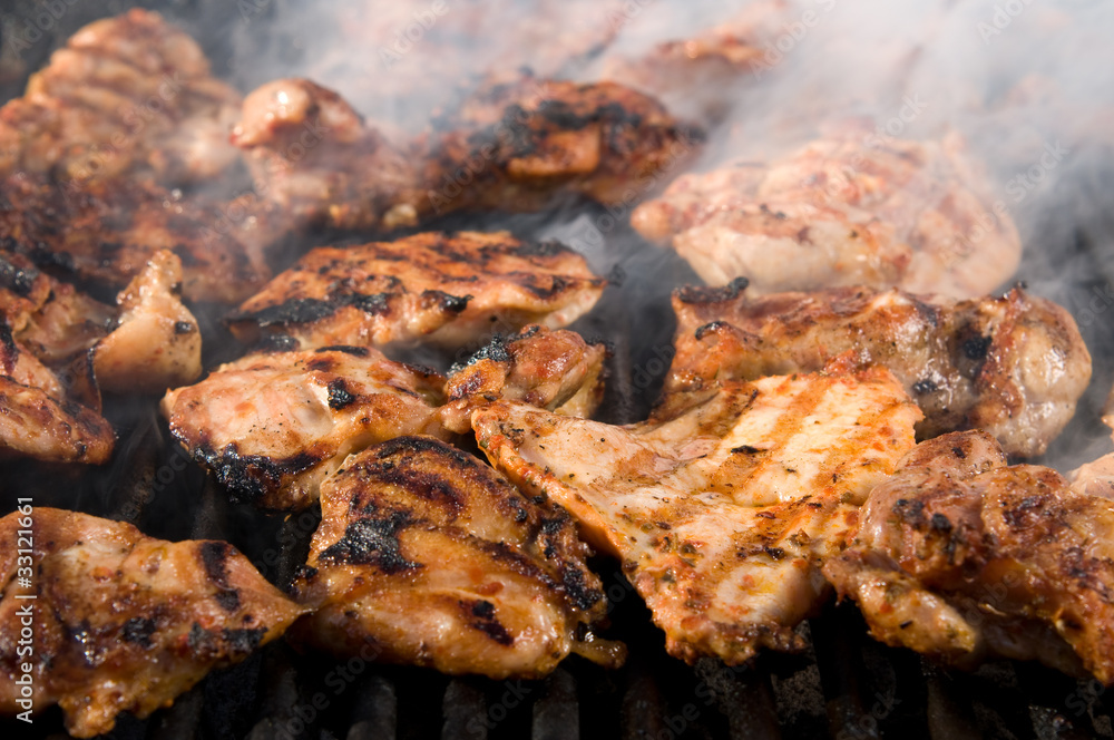 Grilled chicken breasts on barbecue smoking.