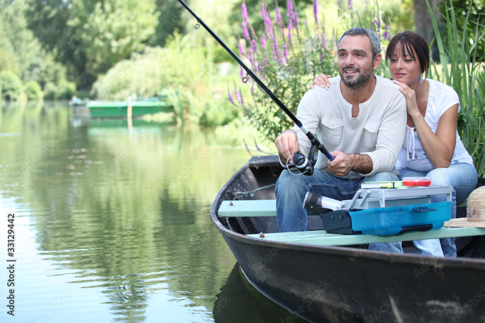 Couple fishing in a small boat on a river Couple fishing in a small boat on a river