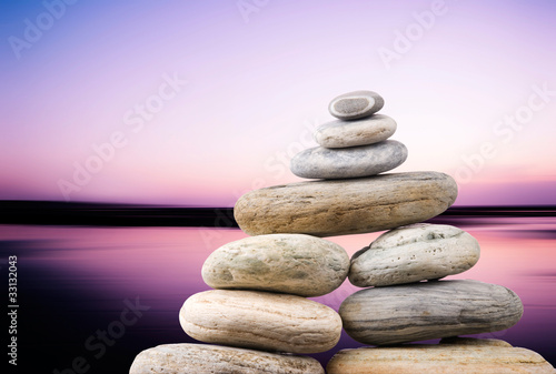 Pebbles stack in peaceful evening with smooth ocean background.