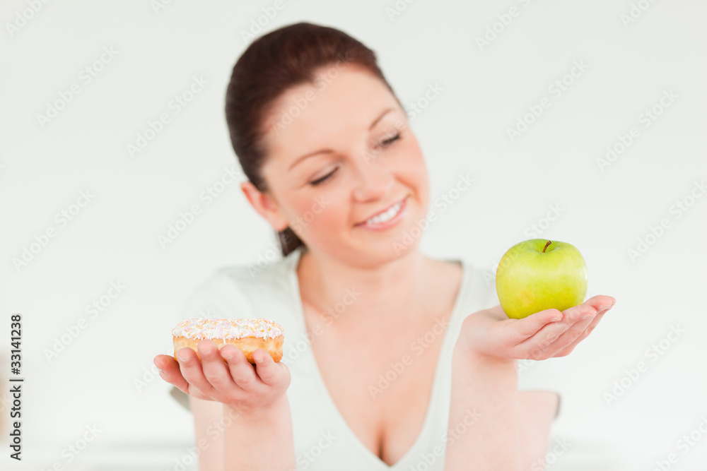 Pretty woman posing while holding a donut and a green apple Pretty woman posing while holding a donut and a green apple