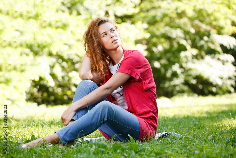 Woman sitting on grass in park Woman sitting on grass in park