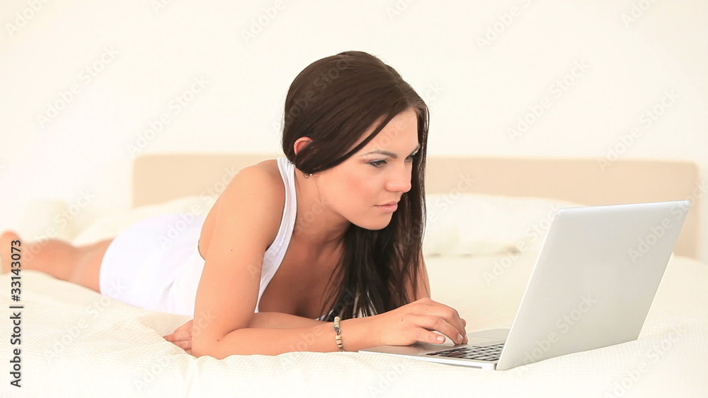 Gorgeous brunette woman relaxing with her laptop while lying Gorgeous brunette woman relaxing with her laptop while lying