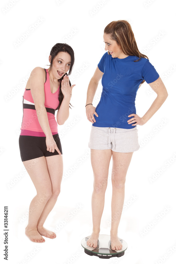 Woman laughing at another on scales Woman laughing at another on scales
