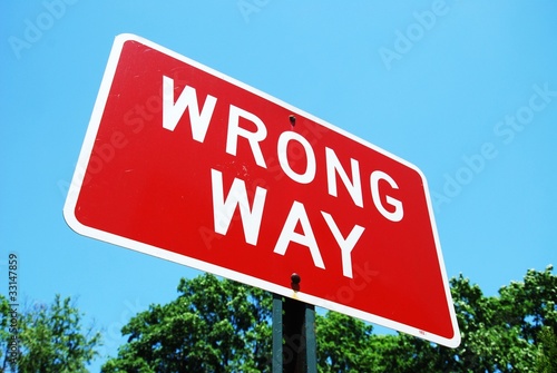 wrong way road sign on a blue sky background