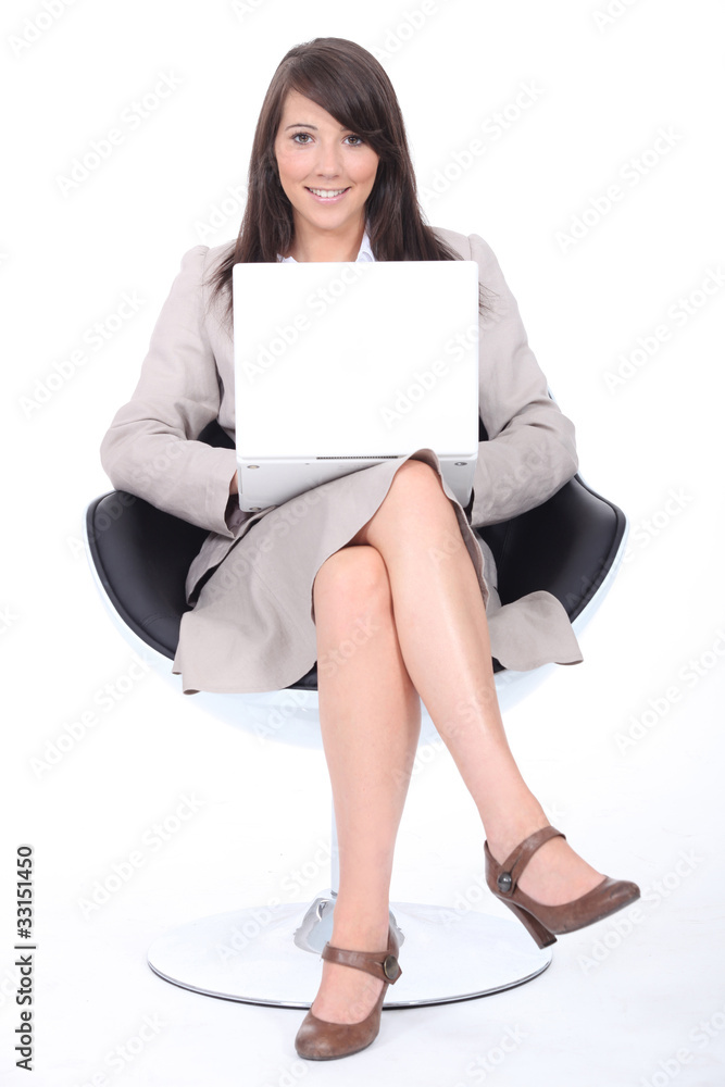 Smart young woman sitting in a swivel chair with a laptop Smart young woman sitting in a swivel chair with a laptop