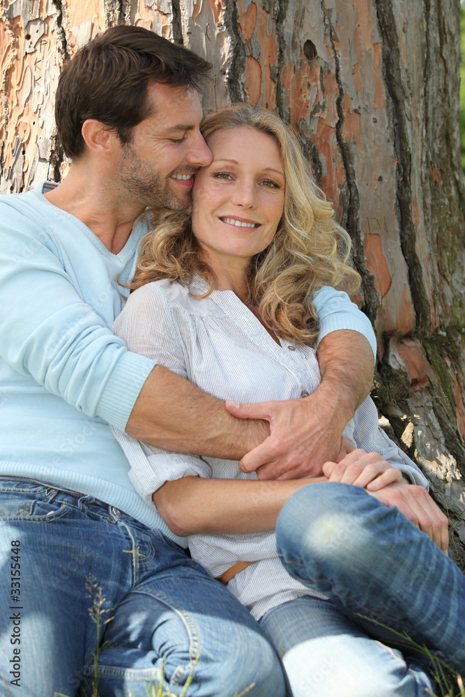 Couple cuddling in front of a tree