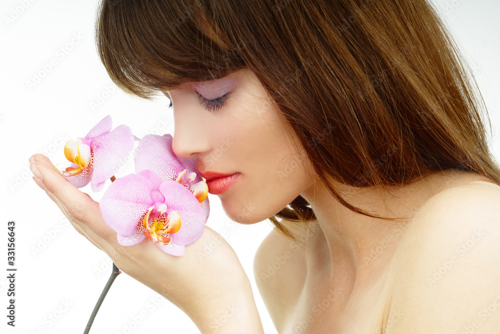 Beautiful woman holding and smelling an orchid flower