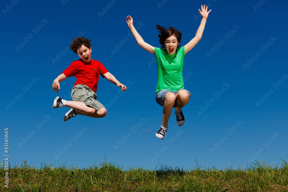 Girl and boy jumping, running against blue sky Girl and boy jumping, running against blue sky